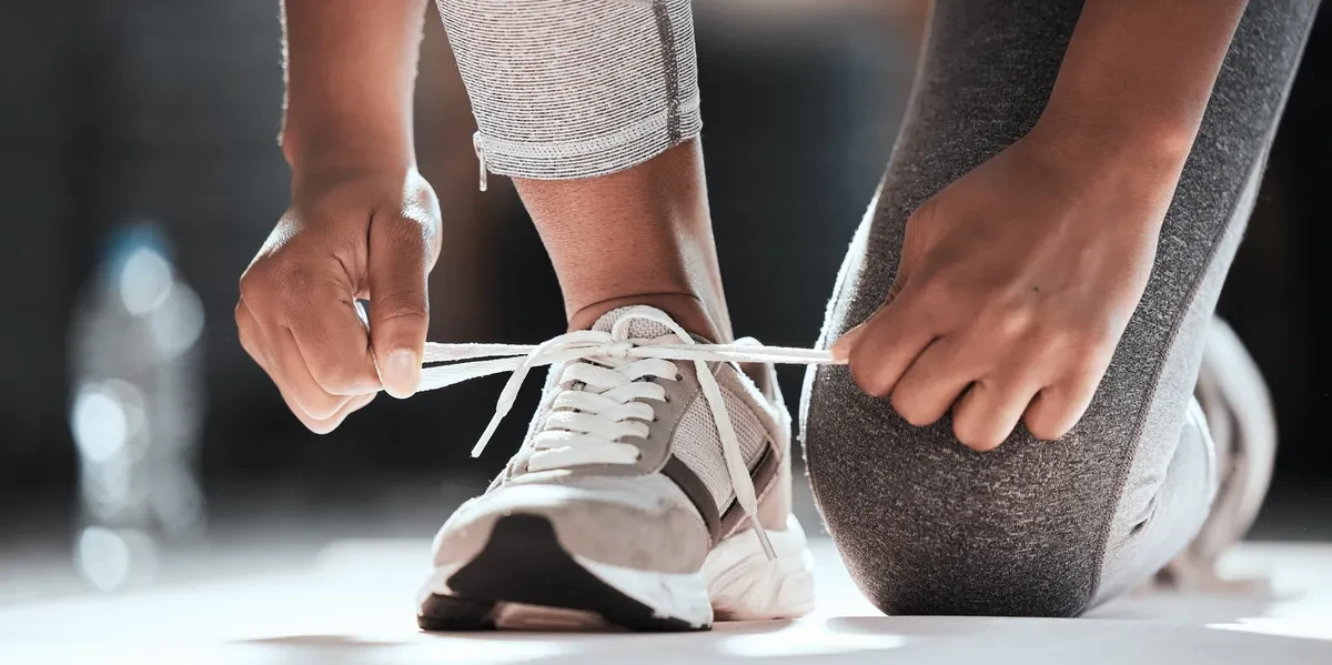Person tying athletic shoes — free workout eBook