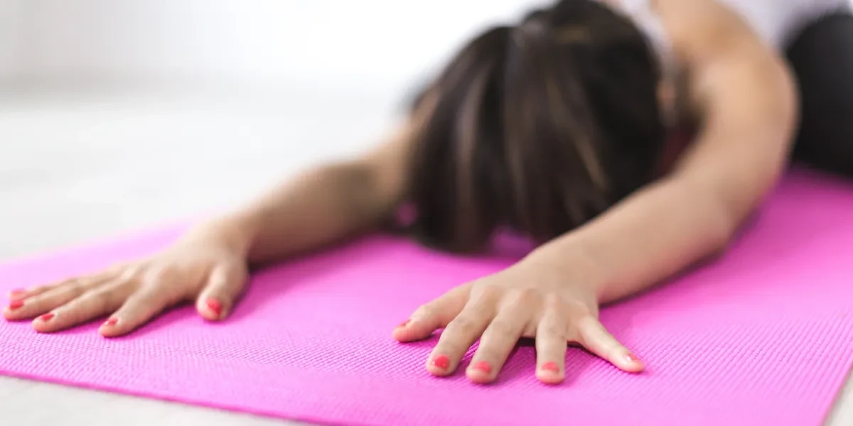 Person in child's pose on a pink yoga mat — yoga block party lesson plan