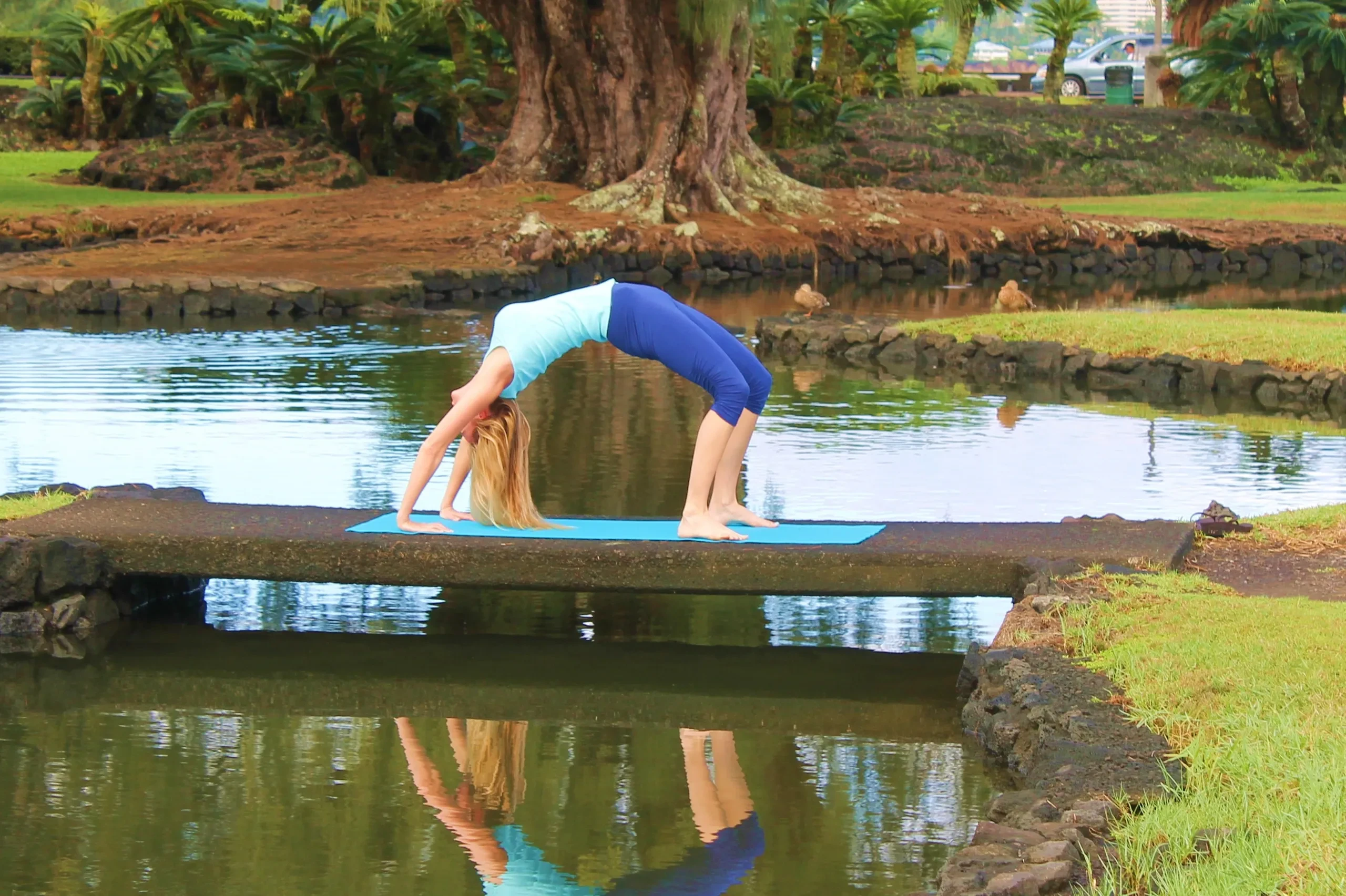 Yoga pose by a tranquil pond surrounded by tropical trees