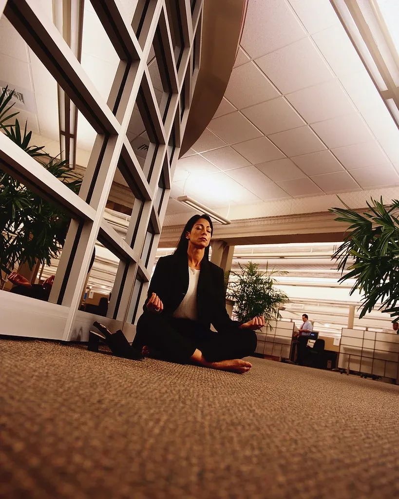 Woman meditating in lotus pose in a modern office building